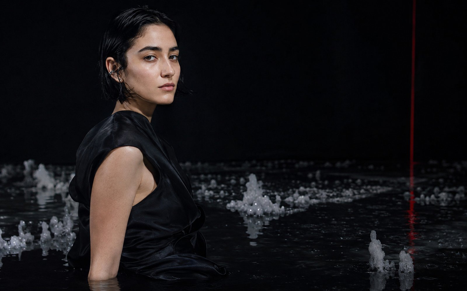 Mira Silt seated in dark water among salt formations for the Salt Memory album era.