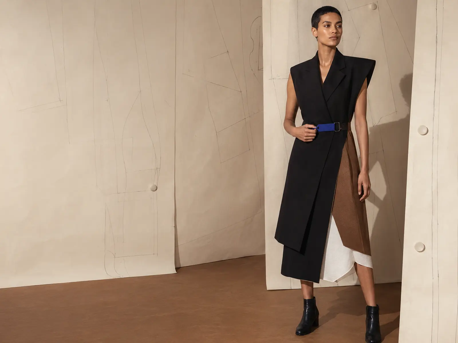 Ninth Form model in sculptural black tailoring with layered construction and a functional blue fastening.